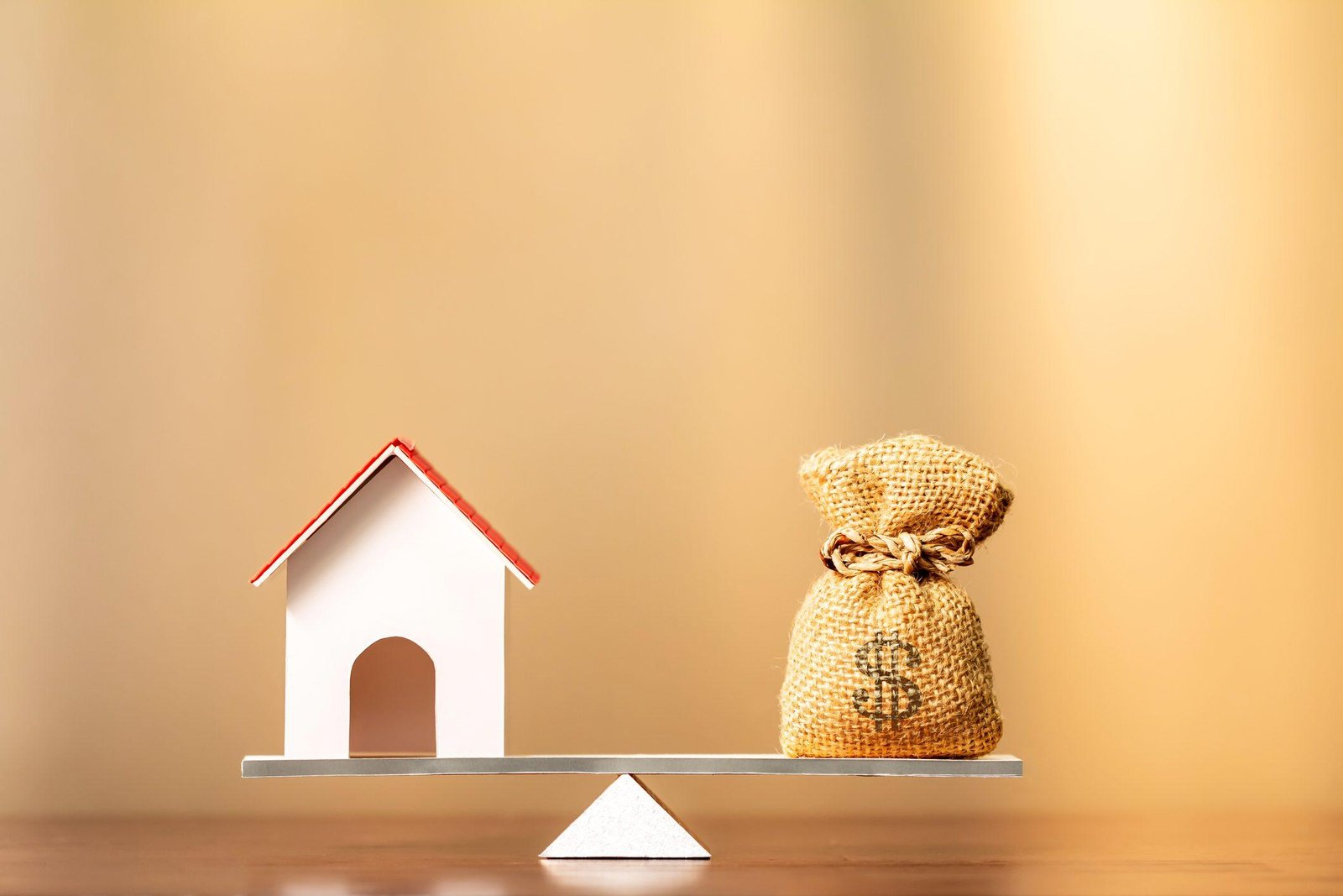 Home and money bag put on the scales with balance on brown background in the office, Saving for buy a new house or real estate and loan for plan business investment in the future concept.